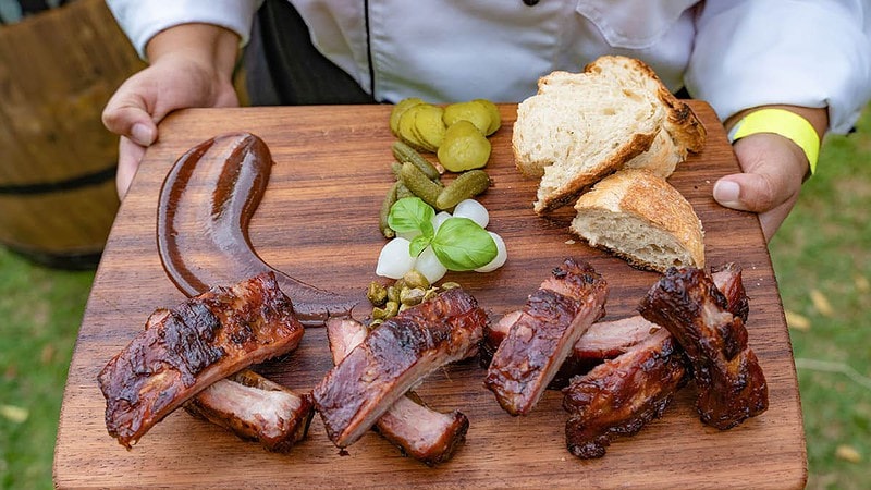 Die Hand hält ein Brett mit Brot, Fleisch und Gemüse
