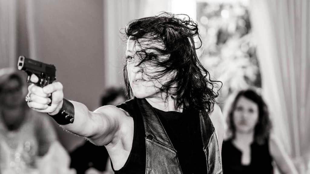 Krimi Dinner - Mordstäuschung-Frau Eine Schauspielerin zielt beim Krimi Dinner in Hamburg mit einer Pistolenattrappe.