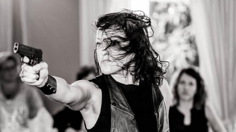 Eine Schauspielerin zielt beim Krimi Dinner in Hamburg mit einer Pistolenattrappe.