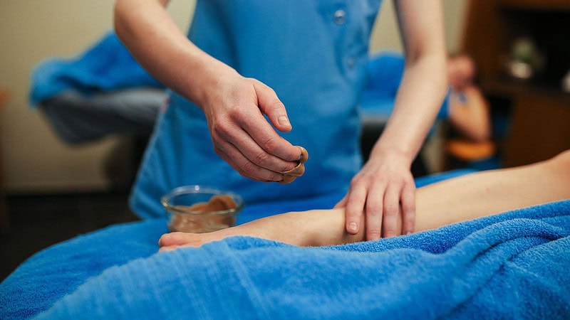 Frau cremt Frau das Bein bei der Massageanwendung süße Verführung in Dresden