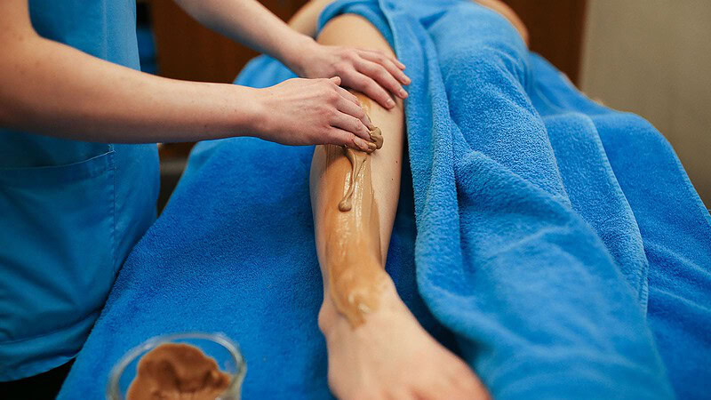 Frau cremt Frau das Bein bei der Massageanwendung süße Verführung in Dresden
