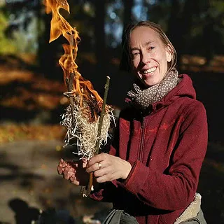 Frau hält Brennende Holzwolle vor sich.