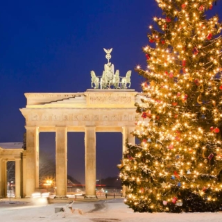 Das Brandenburger Tor in Berlin im Winter. Vor dem Brandenburger Tor steht ein geschmückter Weihnachtsbaum.