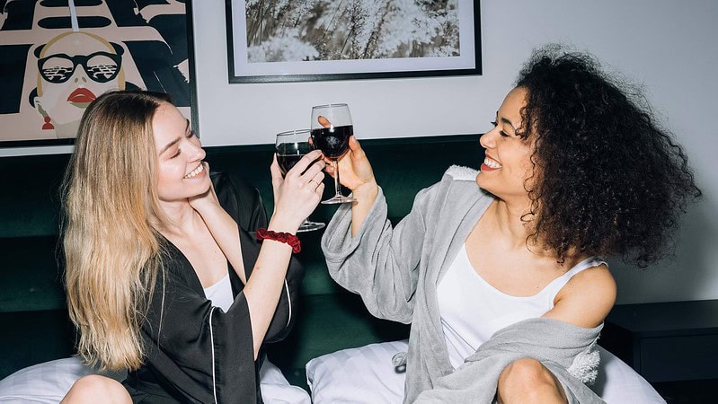 Zwei Frauen feiern zusammen zu Hause und trinken Rotwein