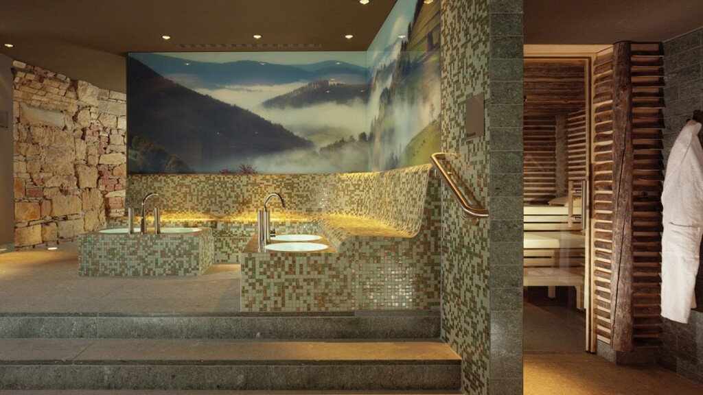 Ein Wellnessbereich mit Sitzmöglichkeiten für ein Fußbad. Rechtes im Bild sieht man einen Teil des Saunaeingangs.