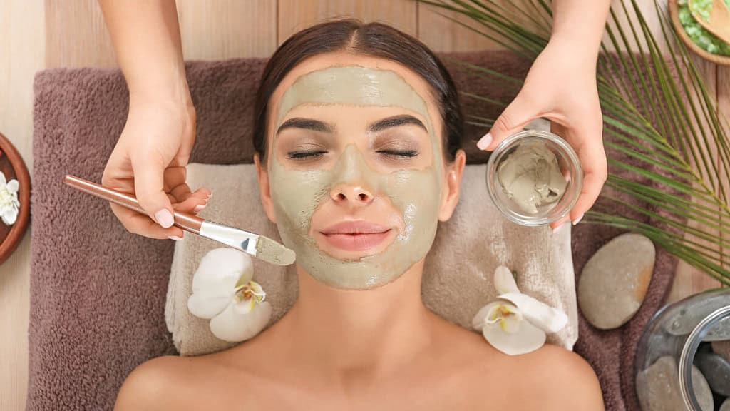 Eine Frau bekommt eine Gesichtsbehandlung und Gesichtsmaske im SPA