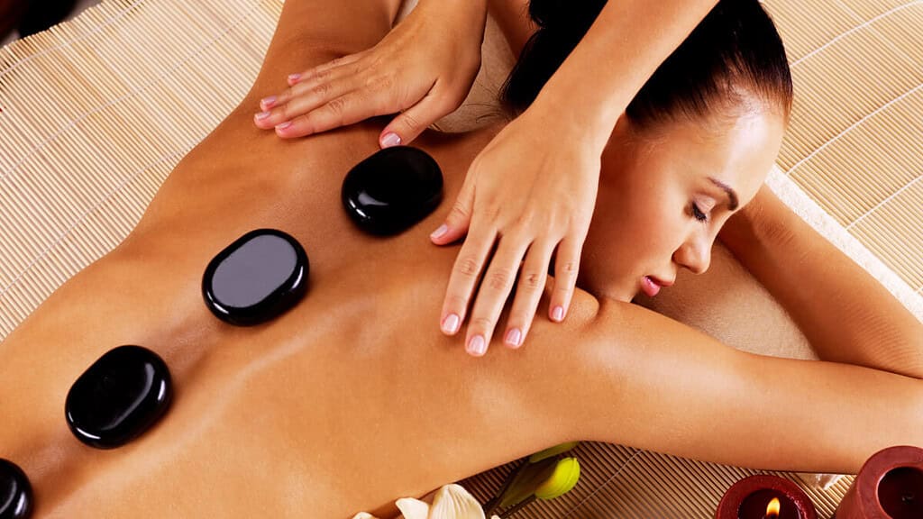 Eine Frau liegt auf einem Massagebett mit heißen Steinen auf ihrem Rücken
