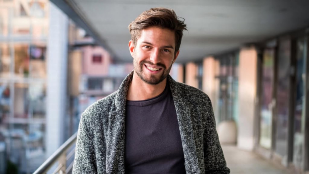 Ein Mann lacht uns posiert während eines Outdoor-Fotoshootings in der Stadt