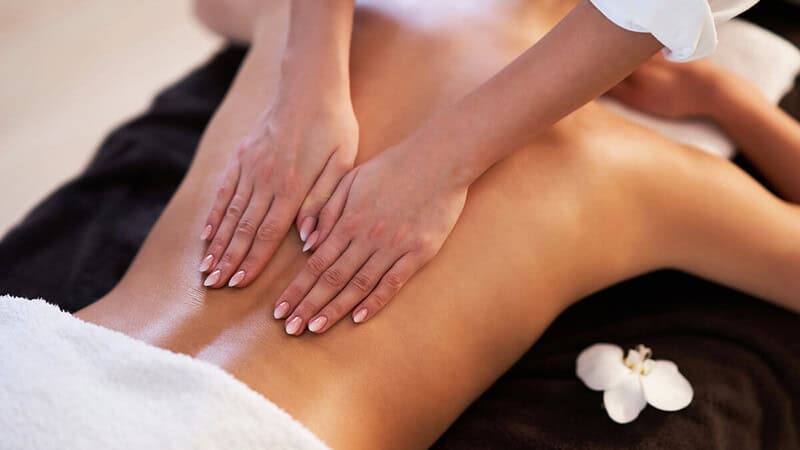 Eine Masseurin wendet Lomi-Lomi-Techniken auf dem Rücken einer Frau an, um sie zu entspannen.