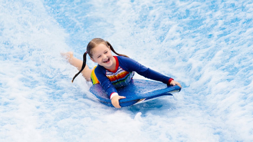 Ein Mädchen lernt wie man surft bei einem Indoor Surfkurs