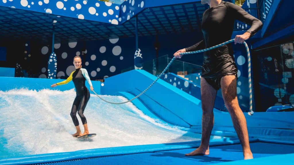 Eine Frau lernt wie man surft bei einem Indoor Surfkurs