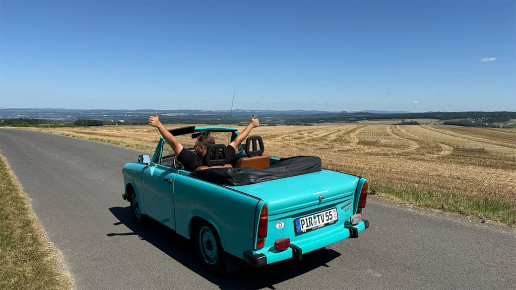 Mann sitzt im Trabant Cabrio und wird von hinten fotografiert