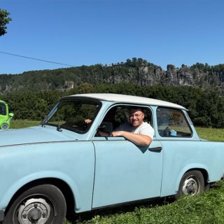 Mann schaut aus blauem Trabant