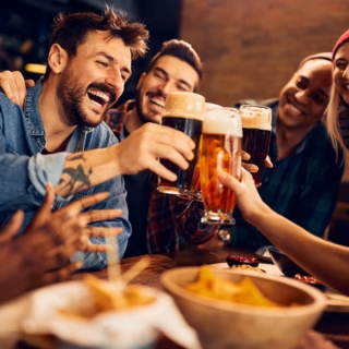 3 Männer trinken Bier in einem Bar und lächeln