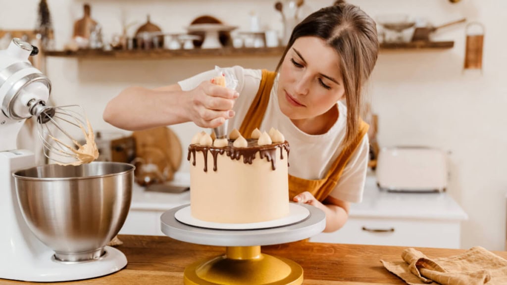 Eine Tortenseminar-Teilnehmerin dekoriert eine selbstgemachte Torte