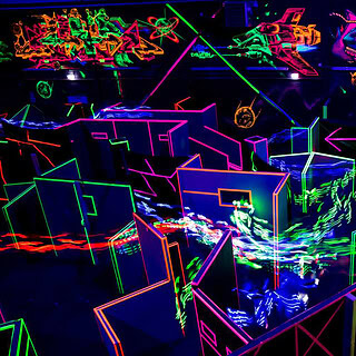 Ein Labyrinth aus Neon leuchtenden Wänden aus der Vogel Perspektive.