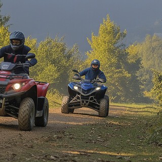 Zwei Quadfahrer düsen auf einem Schotterweg
