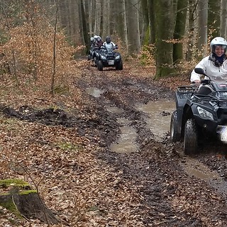 Eine Frau fährt mit ihrem Quad durch einen schlammigen Waldweg