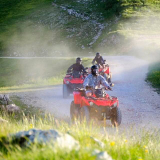 3 rote Quads auf einem Schotterweg zwischen Hügeln