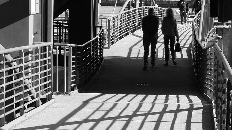 Zwei Fußgänger auf einer Brücke in Schwarz/Weiß Fotografiert