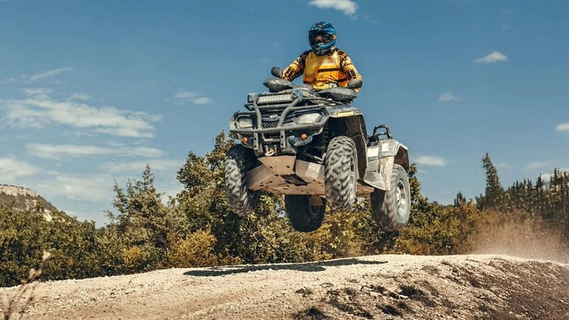 Ein Quad Fahrer der über einen Hügel springt.