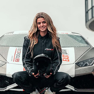 Eine Frau kniet in Rennkleidung und Helm vor einem Lamborghini Huracan.