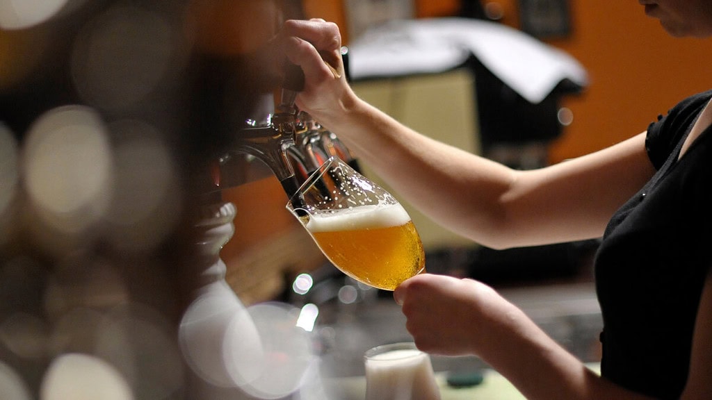 Ein Frau zapft Bier in einer Bar