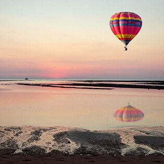 Bunter Heißluftballon über der Ostsee mit Strand und Sonnenuntergang am Himmel- Ballonfahrt-Ostsee