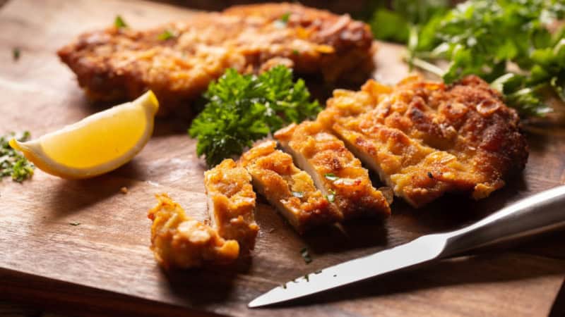 Ein Schnitzel was auf einem Holzbrett in Streifen geschnitten wurde.