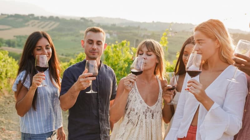 Eine Gruppe von Menschen verkostet einen Rotwein während einer Weinwanderung.