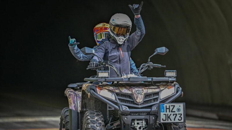 Zwei Fahrer auf einem Quad kommen aus einem Tunnel gefahren und freuen sich.