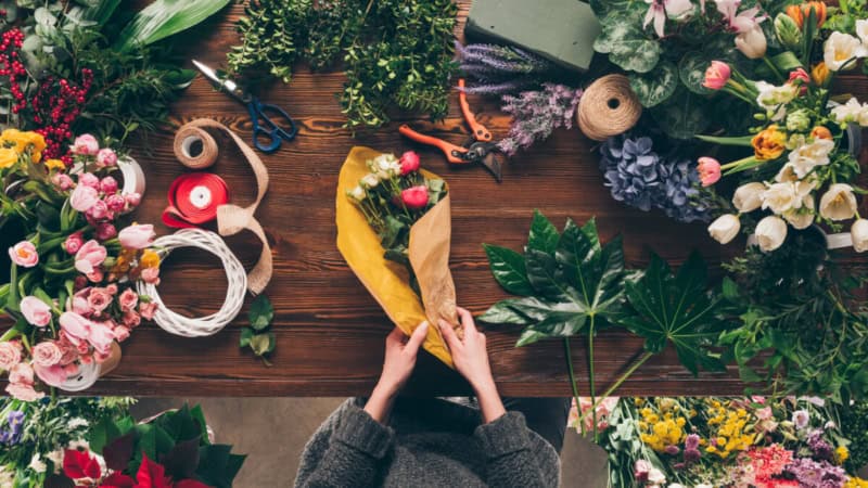 Eine Frau nimmt an einem Floristikkurs teil und bindet einen Blumenstrauß.