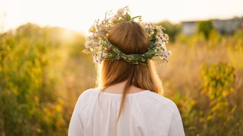 Eine Frau trägt ein Blumenkranz auf ihrem Kopf und posiert für ein Foto im Weinberg.