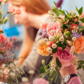 2 Frauen nehmen an einem Floristikkurs teil und lernen wie man Blumensträuße bindet.