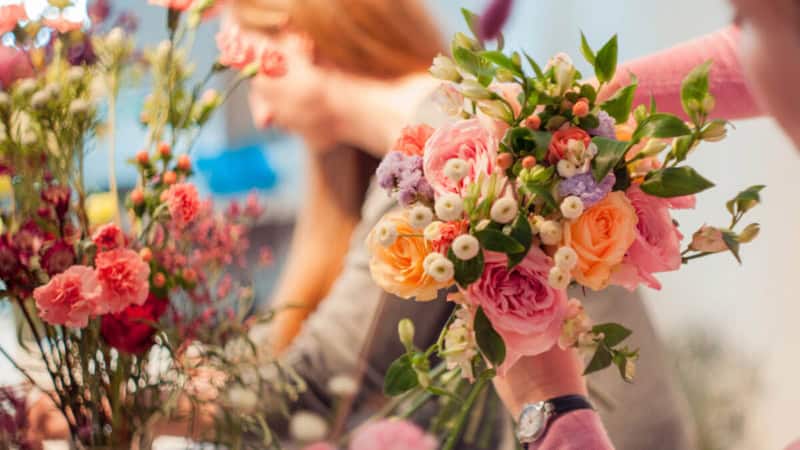 2 Frauen nehmen an einem Floristikkurs teil und lernen wie man Blumensträuße bindet.