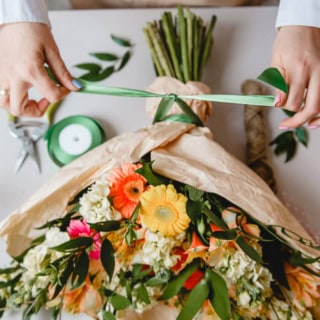Eine Frau bindet einen Blumenstrauß bei einem Floristik Workshop.