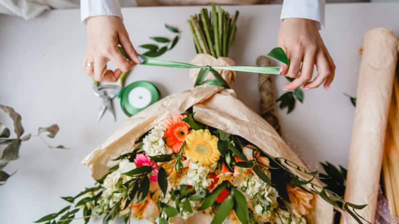 Eine Frau bindet einen Blumenstrauß bei einem Floristik Workshop.