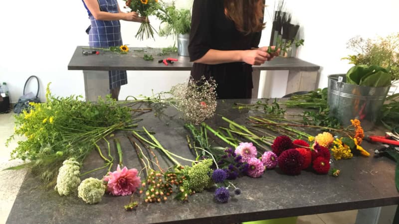 Eine Frau bindet einen Blumenstrauß während eines Floristikkurses.