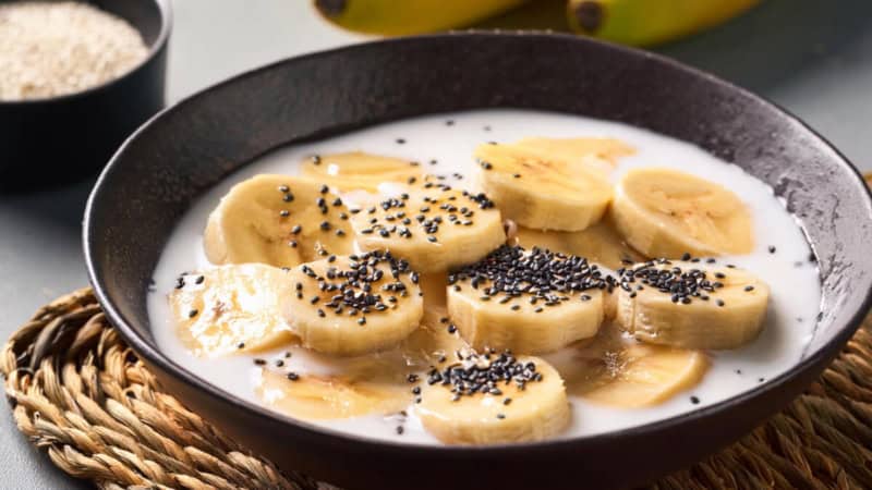 Bananen mit Kokosmilch und Sesam in einem Schüssel.