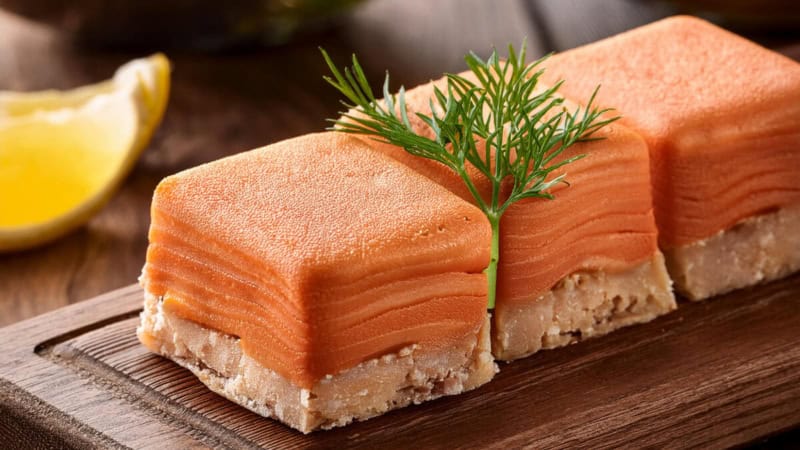 3 Lachs-Pralinen auf einem Schneidebrett.