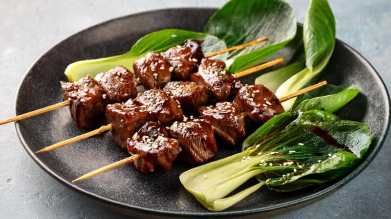 Rindfleisch-Spießen mit Pak Choi auf einem Teller.