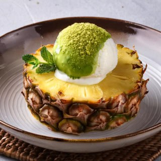 Ein gegrilltes Ananas-Stück mit Matcha-Eis serviert.