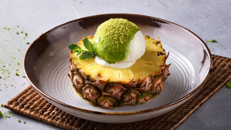 Ein gegrilltes Ananas-Stück mit Matcha-Eis serviert.