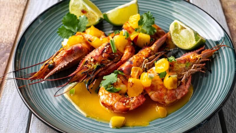 Thai Style gegrillte Garnelen mit Limetten und Soße auf einem Teller.