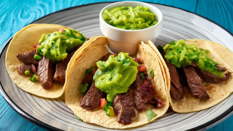 Tacos gefüllt mit Rindfleisch und Guacamole auf einem Teller.