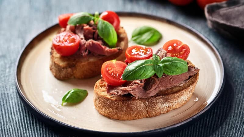 Mediterrane Brötchen mit Fleisch, Tomaten und Basilikum auf einem Teller.
