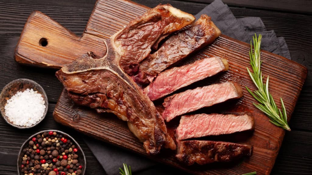 Geschnittenes T-Bone Steak auf einem Schneidebrett.