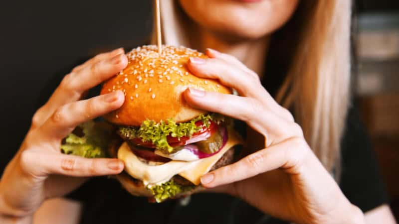 Eine Frau isst einen Burger im Restaurant.