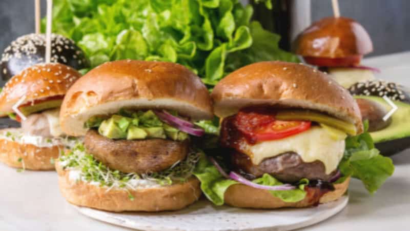 Verschiedene Burgers mit Guacamole liegen auf einem Tisch.