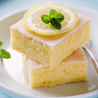 2 Stücke Zitronenkuchen auf einem Teller, mit Minze dekoriert.